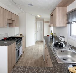 A kitchen with cabinets and a stove at Mariner's Meadow - Hayling Island Holiday Park