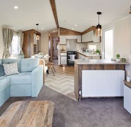 A living room with a sofa and kitchen area at Island Breeze - Hayling Island