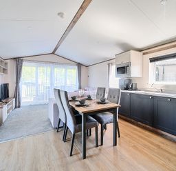 A kitchen and dining area with a table set for four and a living area with a television at Wave Whisperers - Hayling Island in Hayling Island Holiday Park