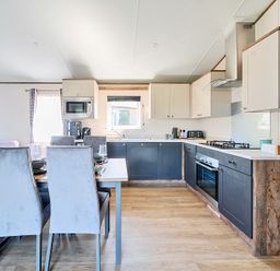 A kitchen and dining area with chairs a table and appliances at Wave Whisperers - Hayling Island in Hayling Island Holiday Park
