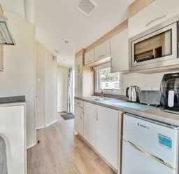 A kitchen area with microwave kettle toaster air fryer and fridge at Golden Dune - Hayling Island in Hayling Island Holiday Park