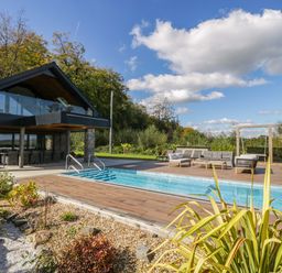 An outdoor area with a swimming pool and seating at Forest Lodge Pontyclun