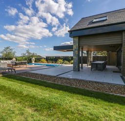 An outdoor area with a swimming pool and seating at Forest Lodge in Pontyclun