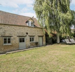 A stone house with windows and a door in the garden at Stable cottage Sopworth near Sherston
