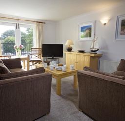 A living room with brown sofas a wooden coffee table a television and chairs at 10 Dartmouth House in Dartmouth