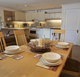 A dining table set with plates and bowls in an open kitchen and living area at 10 Dartmouth House in Dartmouth