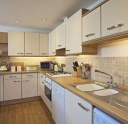 A kitchen with white cabinets a sink a stove a microwave and kitchen utensils at 10 Dartmouth House in Dartmouth