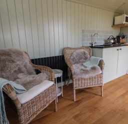 A seating area with chairs and kitchenette at Shepherd's Hut in Wrexham