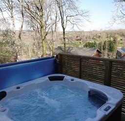 A hot tub on a wooden deck overlooking a landscape at Acorn Lodge Finlakes Holiday Park near Chudleigh