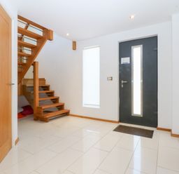 A hallway with stairs and a front door at Shearwater in Rhosneigr