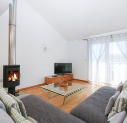 A living room with a wood stove and television stand at Shearwater in Rhosneigr