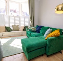 A living room with a green sofa and cushions at Seagull & Chips in Weymouth