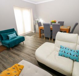 A living room with a sofa and dining table at Amblers Rest in Amble