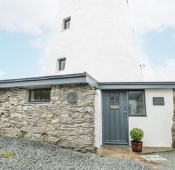 A lighthouse with a stone wall and door at The Old Cornmill Cemaes Bay