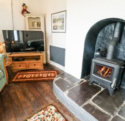 A living room with a television and fireplace at The Old Cornmill in Cemaes Bay