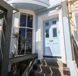An entrance with a blue front door and steps at The Beach Condo in Weymouth