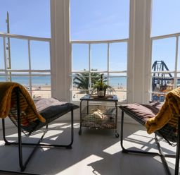 A sunroom with chairs and a table overlooking the beach at The Beach Condo in Weymouth