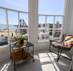 A sunroom with a chair and table overlooking the beach at The Beach Condo in Weymouth
