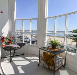 A balcony with a chair and table overlooking the beach at The Beach Condo in Weymouth