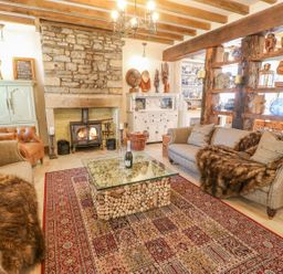 A living room with a stone fireplace a glass coffee table and two sofas at Shaftoe Mews in Haydon Bridge