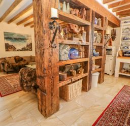 A room with wooden beams shelves displaying ceramics and decorations a sitting area with sofa and artwork on the wall at Shaftoe Mews in Haydon Bridge