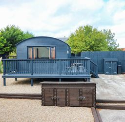 A cabin with a deck and storage box in a garden at Ava Lodge West Mains near Haggerston
