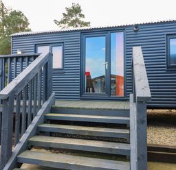 An exterior view of a cabin with steps and a deck at Ava Lodge in West Mains near Haggerston