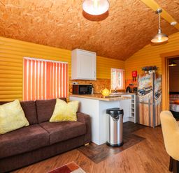 A living room with a sofa and kitchen area at Ava Lodge in West Mains near Haggerston