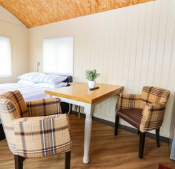 A bedroom with a bed and table with chairs at Masons Hut in West Mains near Haggerston
