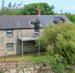 A stone building with a balcony and flowers at The Cottage in St. Ives