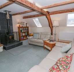 A living room with a wood stove and bookshelves at Yr Hen Ysgoldy