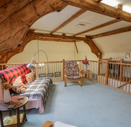 A loft area with a sofa, armchair and table at Yr Hen Ysgoldy 