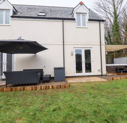 An outdoor seating area with a sofa and hot tub at Poldam in St Austell