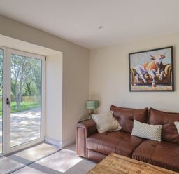 A living room with a sofa and sliding doors at The Fox Den in East Coker