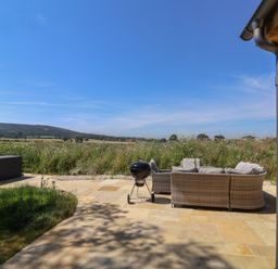 An outdoor area with a sofa and barbecue grill at The Fox Den in East Coker