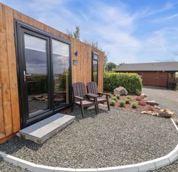 A wooden cabin with chairs outside in an outdoor area at Alken The Hare in Bushmills