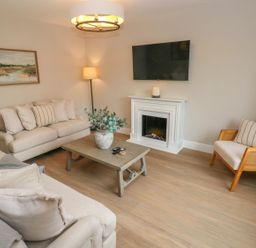 A living room with a sofa, coffee table, and television at Hafan Y Gof Newcastle Emlyn