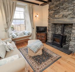A living room with a sofa and fireplace at Stoker’s Cottage in Bowness-On-Windermere