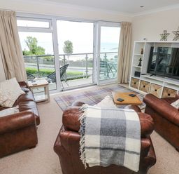 A living room with brown leather furniture and a view of the sea at Lifeboat Lookout in Tenby