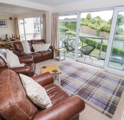 A living room with leather sofas and a view of the balcony at Lifeboat Lookout in Tenby