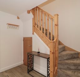 A hallway with a staircase and a table at 1 The Stables Highbridge