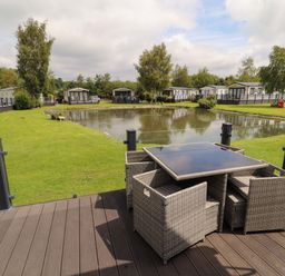 An outdoor area with a table and chairs overlooking a pond at 22 Yealand Carnforth