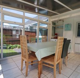 A conservatory with a dining table and chairs at Swn Y Don