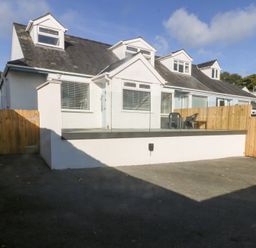 A house with a deck and chairs at Swn Y Don in Llanbedrog