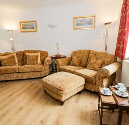 A living room with sofas and a tea set at No.1 Vanderhoof Way Saundersfoot
