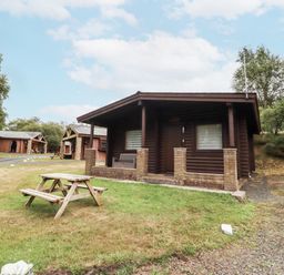 A log cabin with a picnic table in front at Farnes Lodge Longframlington