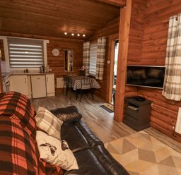 A living room with a sofa and kitchen in Farnes Lodge Longframlington
