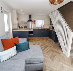 A kitchen with a sofa and staircase at Seahorse Cottage in Chathill