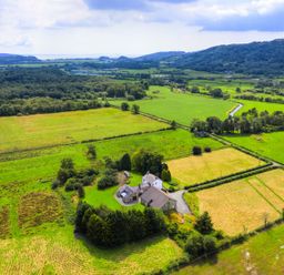 An aerial view of a house surrounded by fields and trees at Grove House in Grange-Over-Sands