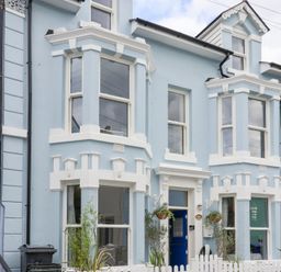 A house with multiple windows and a blue door at Still Waters in Brixham